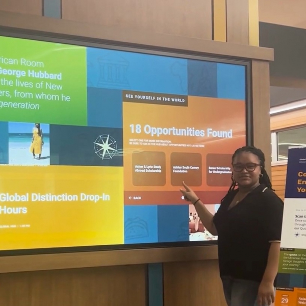 Student pointing to opportunities on the Engagement Wall in the Pitt Global Hub